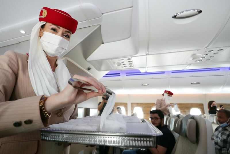 Cabin crew hand out hot towels to passengers seated in the premium economy cabin. 