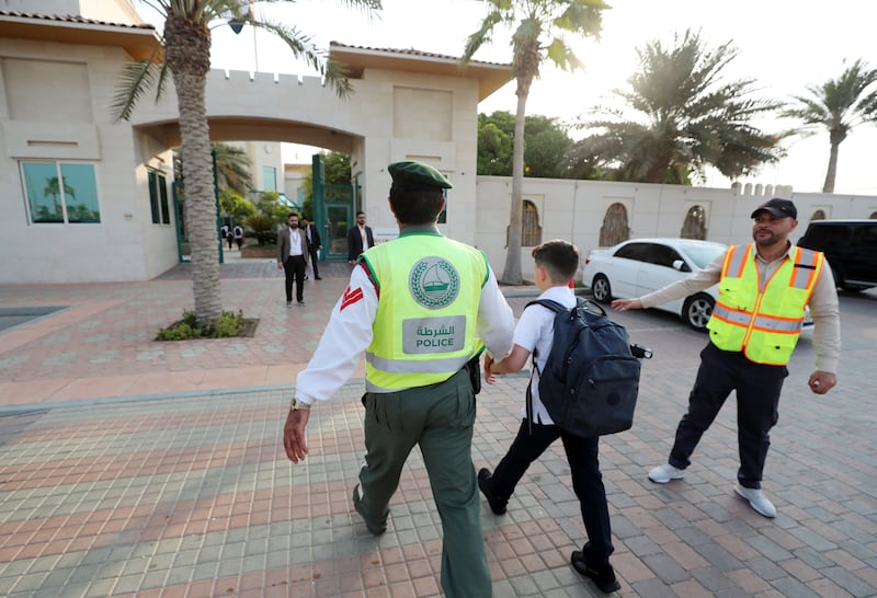 A police officer helps a pupil outside the Research Science Private School in Al Warqaa, Dubai. Chris Whiteoak / The National