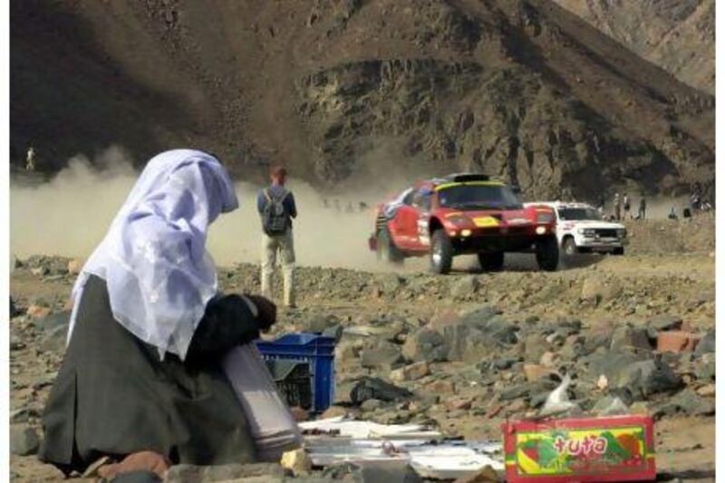 An Egyptian vendor watches German driver Jutta Kleinschmidt who races through the mountains of Wadi Masdud in South Sainai, Egypt, in January 2003 during a special stage a day before the last stage of the Dakar Rally. AP Photo