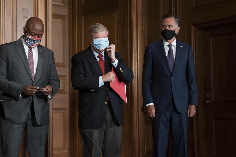 Senator Lindsey Graham, a Republican from South Carolina, center, adjusts a protective mask during a news conference with Republican Senators at the U.S. Capitol in Washington, D.C., U.S., on Monday, July 27, 2020. Senate Republicans presented their $1 trillion plan to bolster the pandemic-ravaged U.S. economy in a series of bills that would trim extra unemployment benefits, send $1,200 payments to most Americans and shield businesses, schools and other organizations from lawsuits stemming from coronavirus infections. Photographer: Sarah Silbiger/Bloomberg
