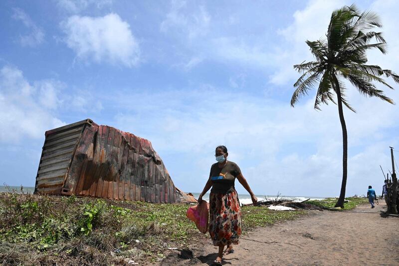 A resident walks past the remains of a burnt container washed ashore. AFP