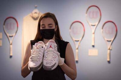 An assistant poses with Swiss tennis champion Roger Federer's Nike Air Jordans from the 2014 US Open during a photocall at Christie’s auction house in central London on June 21, 2021. / AFP / Tolga Akmen
