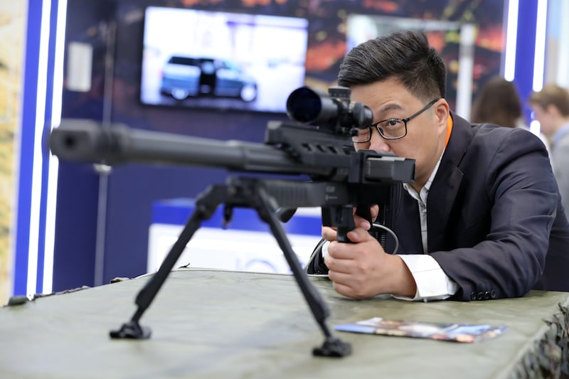 Han Bing peers through the scope of a sniper rifle at the Steyr arms stand