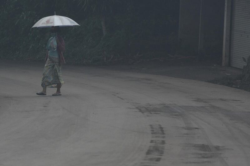 A woman uses an umbrella as she walks through ash from Mount Agung volcano during an eruptiuon in Bebandem Village, Karangasem, Bali, Indonesia on November 26, 2017. Antara Foto / Fikri Yusuf / via Reuters