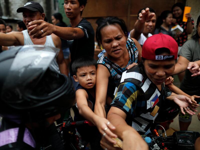 Filipino villagers receive bags of goods from motorcycle riders during the aid operation. EPA