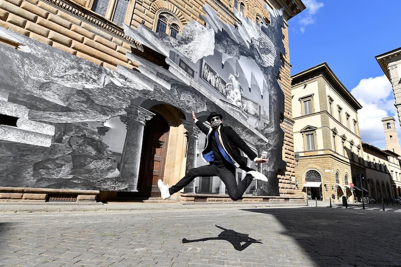 French contemporary artist JR jumps in front of his art installation on the facade of Strozzi Palace titled 'La Ferita (The Wound)', and showing an optical illusion of a black and white interior of the elegant Renaissance palace, as the artist efforts to make a statement on accessibility to culture in the coronavirus disease (COVID-19) era, in Florence, Italy. Reuters
