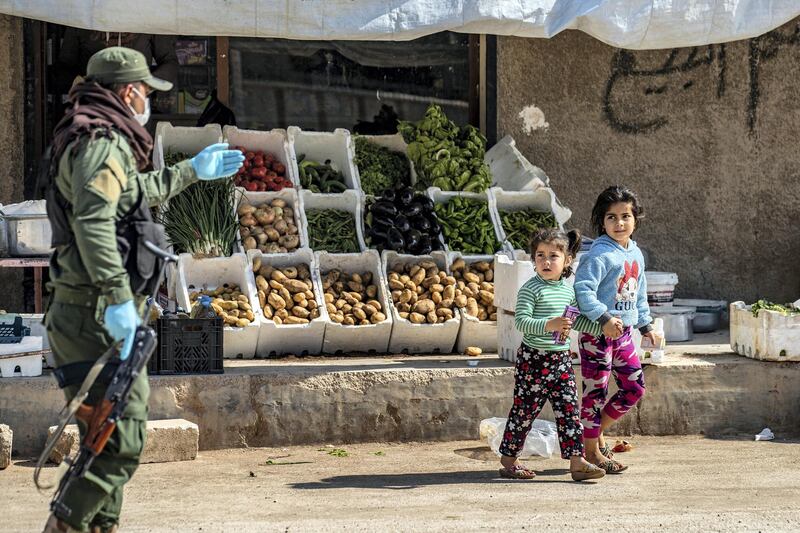 A member of the Kurdish Internal Security Forces of Asayesh urges children to return home, in Syria's northeastern city of Hasakeh on April 30, 2020, following measures taken by the Kurdish-led local authorities there, to limit the spread of the novel coronavirus. (Photo by DELIL SOULEIMAN / AFP)