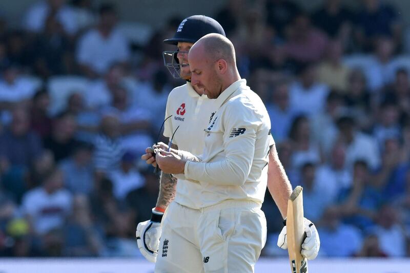 Jack Leach cleans his glasses as he and England's Ben Stokes speak during a break in play. AFP