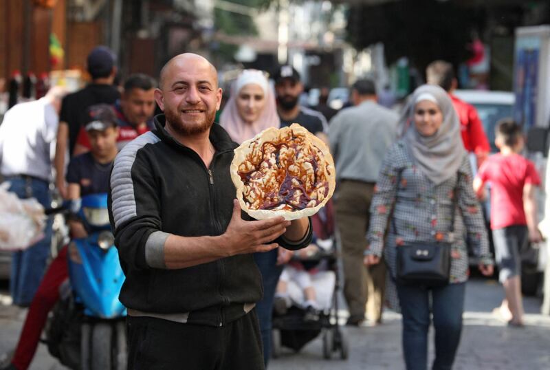 A Syrian vendor displays the traditional sweet known as "al-Naem", commonly served during the Muslim holy month of Ramadan, in Damascus' Shaqhoor neighbourhood on April 28, 2021. Year after year Ramadan meals become more frugal in war-torn Syria as the economy worsens, but Damascus dwellers say a traditional wafer-thin crispy pancake called "naaem" is there to stay. During the Islamic fasting month, Damascus residents flock just before sundown to buy the deep-fried sweet from ambulant sellers making them in bubbling cauldrons all over the sidewalks. The crunchy pastry -- also called "Ramadan bread" -- is prepared by dropping a thin circle of dough into hot oil until it snaps like a crisp. / AFP / LOUAI BESHARA
