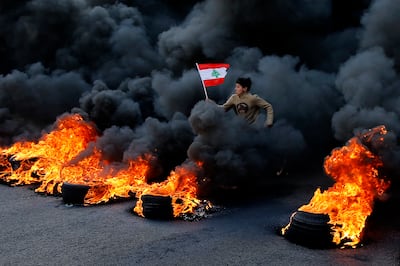 An anti-government demonstrator runs across lighted tyres during a protest in the town of Jal El Dib, north of Beirut, Lebanon. AP