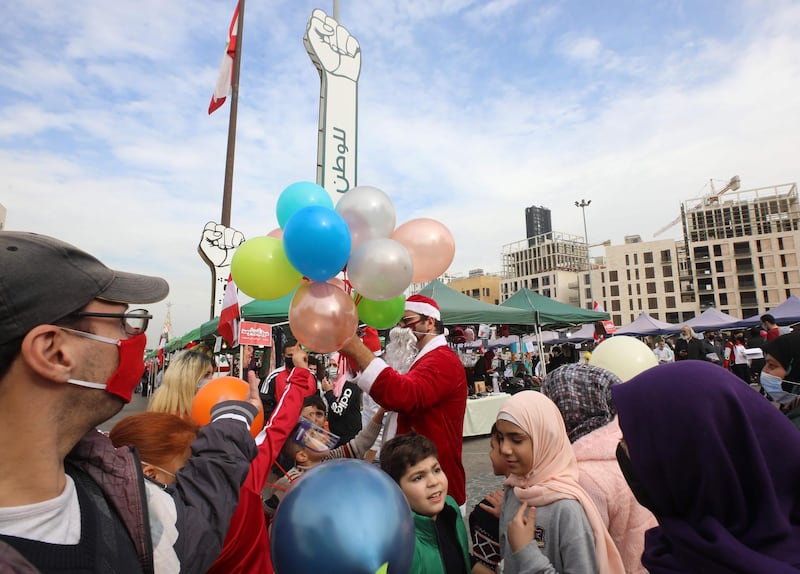 A Lebanese man wearing a Santa Claus outfit, entertains children at a Christmas market set up on Martyr's square, the epicentre of anti-government protests, in the capital Beirut's downtown district. AFP