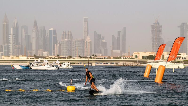 An athlete rides a jet-powered surfboard on the first day of the Dubai watersport festival, organised by the Dubai International Marine Club (DIMC), near the Burj Khalifa skyscraper in the Gulf emirate on June 25, 2020.  / AFP / KARIM SAHIB
