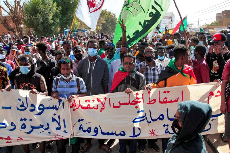 People march with a banner reading "down with the transitional council" in Arabic.  AFP