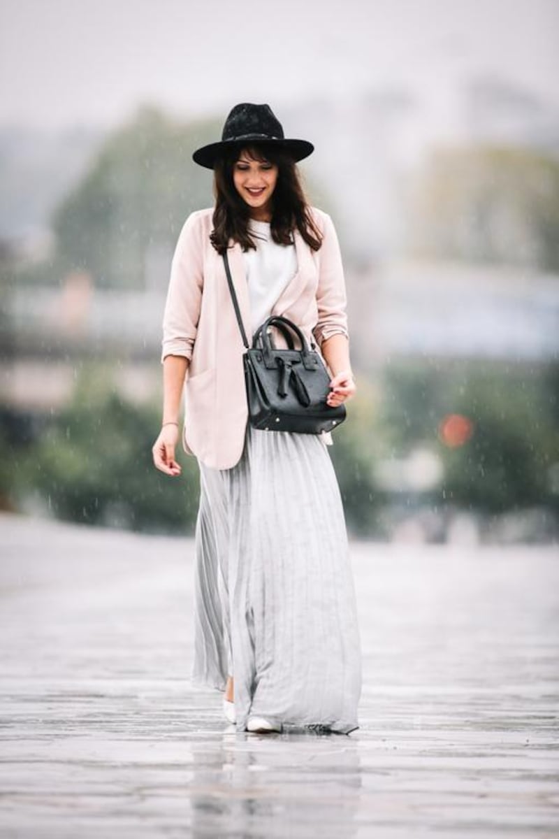 Sarah Benziane (fashion and lifestyle blogger - Les colonnes de Sarah) wears a Zara white top, a New Look pink jacket, a She Inside silver gray skirt, Bershka shoes, and a Dezzal black bag. Berthelot / Getty Images
