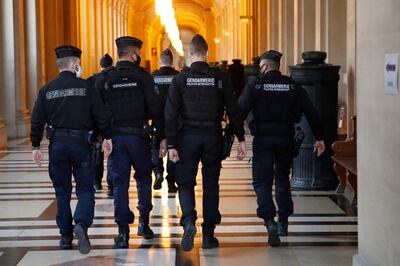 French gendarmes walk in the corridor of the hall of justice, Thursday, Dec. 17, 2020 in Paris. Ayoub El Khazzani went on terror charges for appearing on a train with an arsenal of weapons and shooting one passenger in 2015. The proceedings end Thursday with the verdict. (AP Photo/Francois Mori)