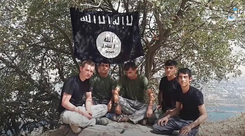 This grab taken from video, made available by Aamaq news agency of the Islamic State group, shows five men sitting on a hill against the backdrop of a black-and-white IS flag and declaring allegiance to IS leader Abu Bakr al-Baghdadi. The Islamic State group on Tuesday July 31, 2018 claimed responsibility for a car-and-knife attack on Western tourists cycling in Tajikistan that killed two Americans and two Europeans. (Aamaq news agency of the Islamic State group via AP)
