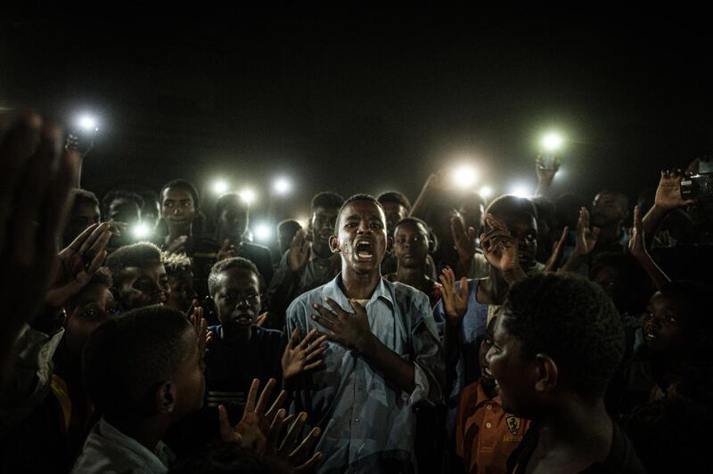 A photo by Yasuyoshi Chiba that shows people chanting slogans as a young man recites a poem, illuminated by mobile phones, before the opposition's direct dialog with people in Khartoum on June 19, 2019, wins the "Picture of the Year" award in the World Press Photo 2020 Contest. Yasuyoshi Chiba / AFP