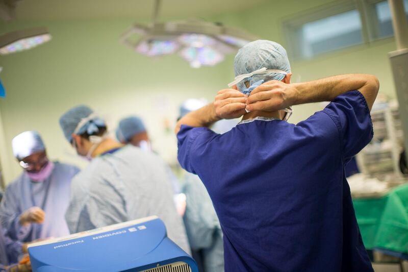 FILE: A member of the medical staff secures his face mask whilst working inside an operating theater at Queen Elizabeth Hospital Birmingham, part of the University Hospitals Birmingham NHS Foundation Trust, in Birmingham, U.K., on Monday, Feb. 20, 2017. As the U.K. government proposes spending 160 million pounds ($207 million) to support medical research and health care we select our best archive images on health. Photographer: Matthew Lloyd/Bloomberg