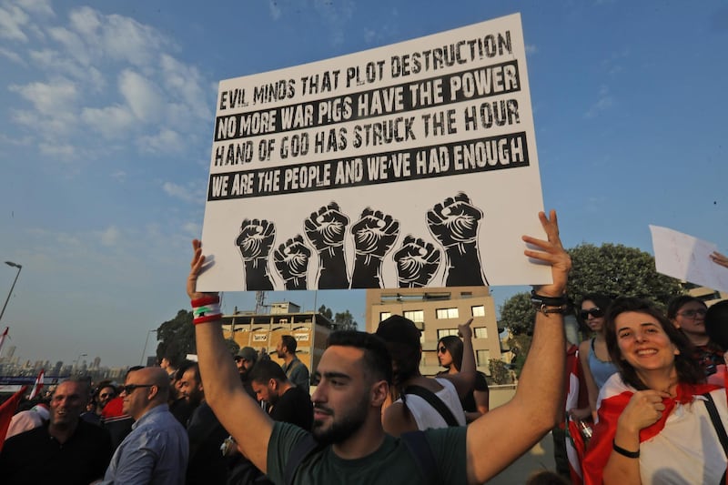 A Lebanese demonstrator carries a placard during a gathering on the road leading to the Presidential Palace in Baabda, on the eastern outskirts of Beirut on November 13, 2019, nearly a month into an unprecedented anti-graft street movement. Street protests erupted, the night before, after President Michel Aoun defended the role of his allies, the Shiite movement Hezbollah, in Lebanon's government. Protesters responded by cutting off several major roads in and around Beirut, the northern city of Tripoli and the eastern region of Bekaa. / AFP / Anwar AMRO
