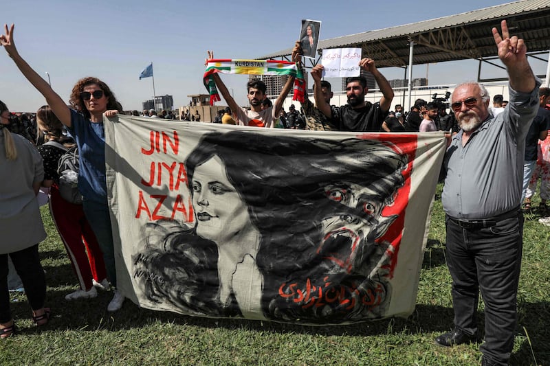 A man and a woman hold up a banner with an image of Amini. AFP