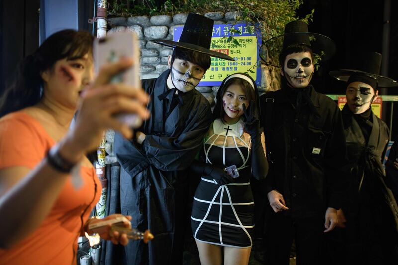 Revellers wearing Halloween make-up pose for a photo as they walk past bars and restaurants in the popular nightlife district of Itaewon in Seoul. AFP