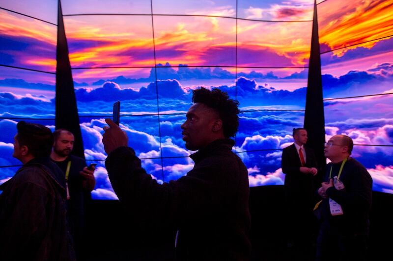 People walk through a display of LG OLED televisions at CES in Las Vegas, Nevada, January 9, 2018.    / AFP PHOTO / DAVID MCNEW