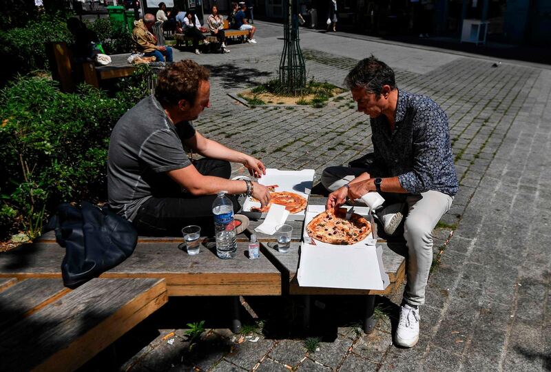 People eat outside after buying pizza for take away, in Paris, after France eased lockdown measures taken to curb the spread of the COVID-19.  AFP