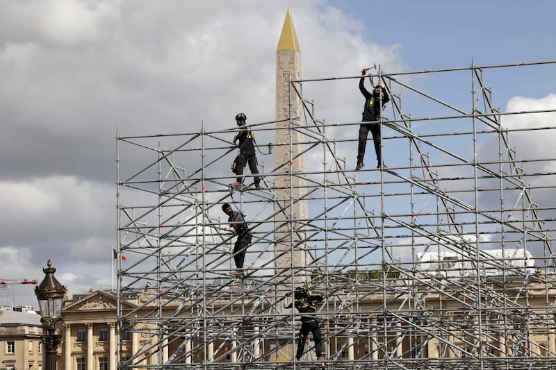 Workers construct banks of seating in front of the obelisk at the La Concorde Urban Park site in central Paris. AFP