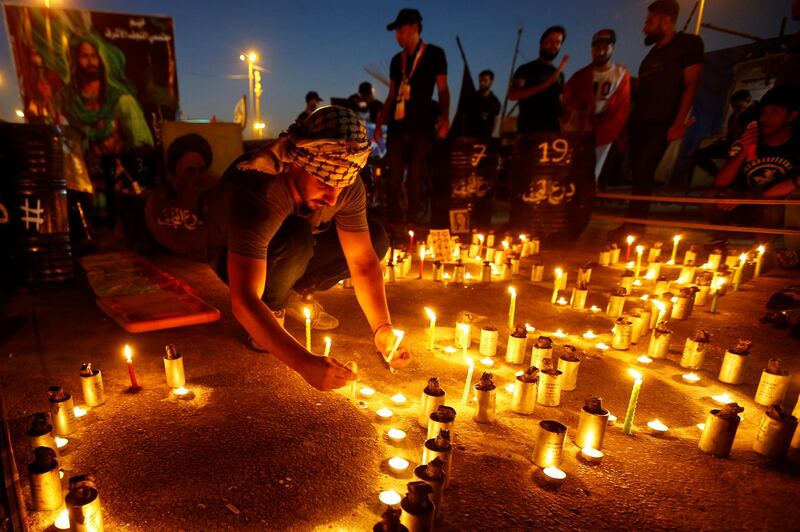 A man lights candles as Iraqi demonstrators gather to mark the first anniversary of the anti-government protests, in Najaf, Iraq. Reuters