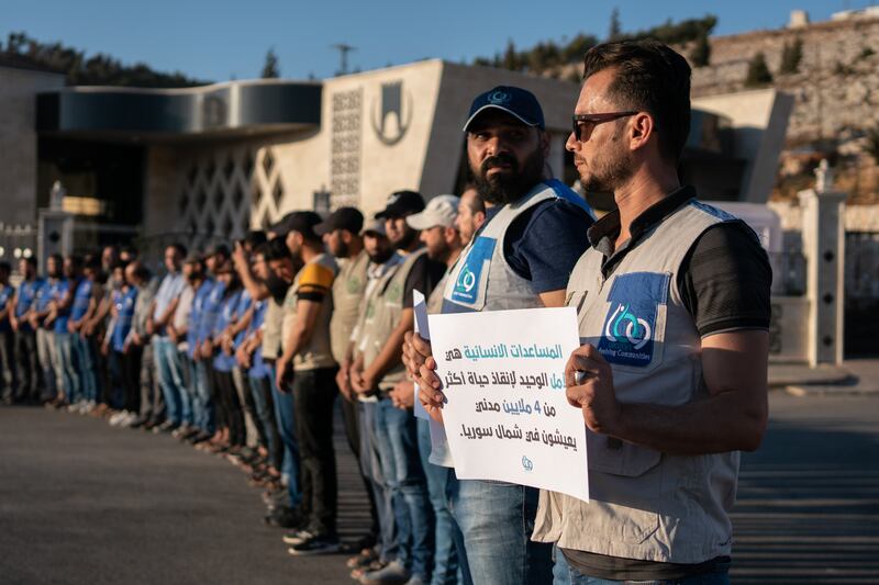 Activists at a vigil near Bab al-Hawa in Idlib with placards calling for the resumption of cross-border aid  after Russia refused to extend the UN Security Council's mandate for cross-border relief operations