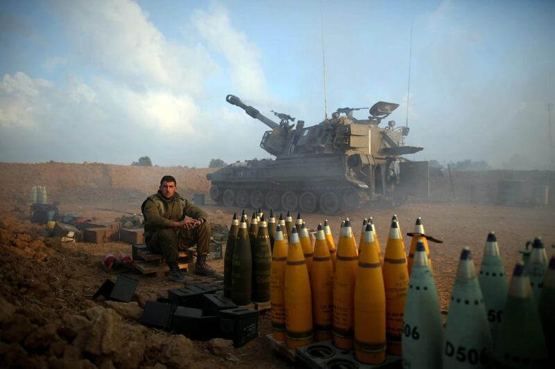 An Israeli soldier rests next to artillery shells near the Israeli border with Gaza. Abir Sultan / EPA