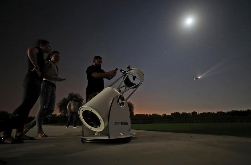 People stand to watch a partial lunar eclipse through a telescope at the Al Thuraya Astronomy Center in Dubai. AP Photo/Kamran Jebreili