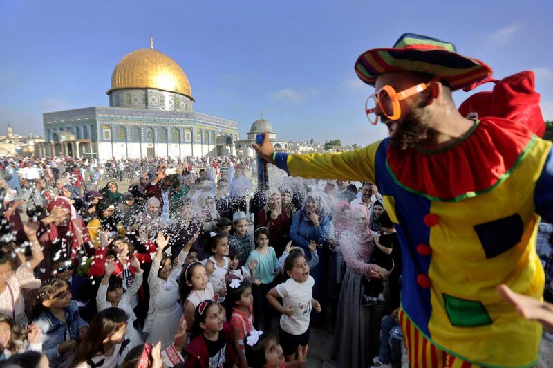 A clown sprays foam towards a group of children during Eid al-Adha near the Dome of the Rock Mosque in the Al Aqsa Mosque compound in Jerusalem's old city. AP Photo