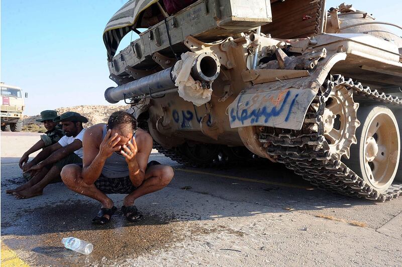 epa02881152 A Libyan rebel fighter washes his face in the shade of a captured tank at a checkpoint near Ras Lanuf, east of Tripoli and Sirte, Libya, on 25 August 2011. Libyan rebel leader Mustafa Abdel Jalil said more than 20,000 people have died during the six-month-old rebellion to oust Muammar Gaddafi. Since February, rebels have been fighting Gaddafi's forces in a bid to end his 42 years in power.  EPA/MOHAMED OMAR *** Local Caption ***  02881152.jpg