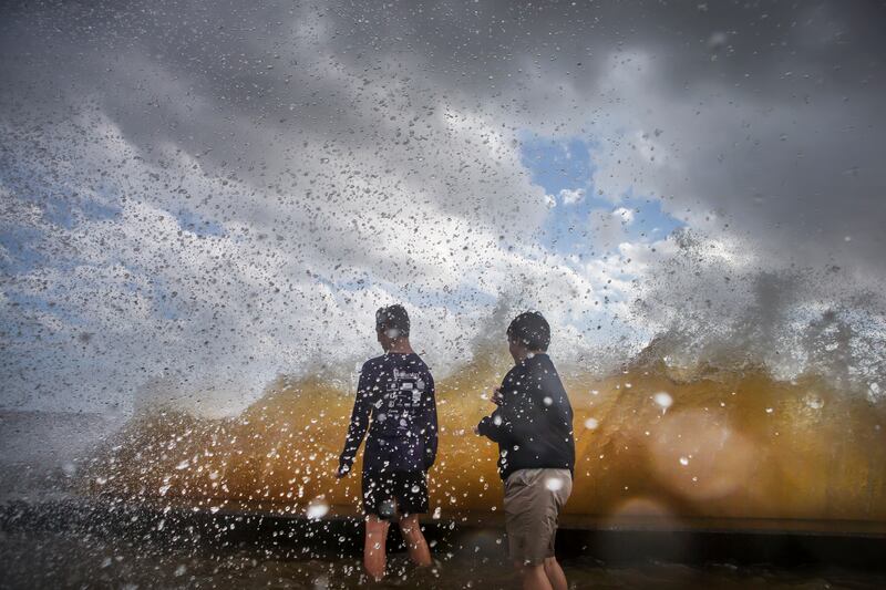 Ryder Hernandez and his friend Jack Lafleur get hit by a wall of water while watching the waves as strong winds from Tropical Storm Harvey move across southern Louisiana. Chris Granger / NOLA.com The Times-Picayune via AP