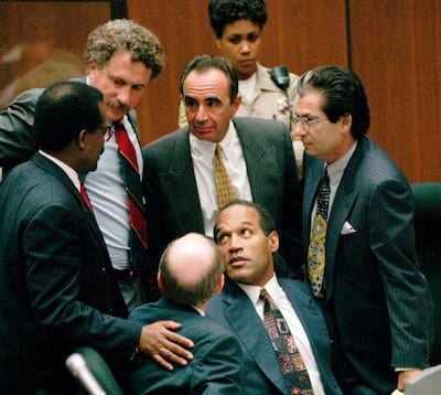 FILE--In this Sept. 28, 1995 file photo, O.J. Simpson is surrounded by his "Dream Team" defense attorneys from left, Johnnie L. Cochran Jr., Peter Neufeld, Robert Shapiro, Robert Kardashian, and Robert Blasier, seated at left, at the close of defense arguments in Los Angeles.  For an earlier generation, OJ Simpson was a symbol of racial tension and uneven justice.  While the issues around race and policing remain today, Simpson's racial symbolism is largely seen as a relic. (AP Photo/Sam Mircovich, Pool, File)