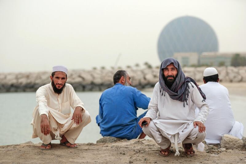 Abu Dhabi, U.A.E., July 29, 2018. Hazy and dusty weather with overcast skies.at the  Al Raha Mall area.  Pakistani delivery truck workers take a break at the Al Raha beach shoreline.
Victor Besa / The National
Section:  NA
