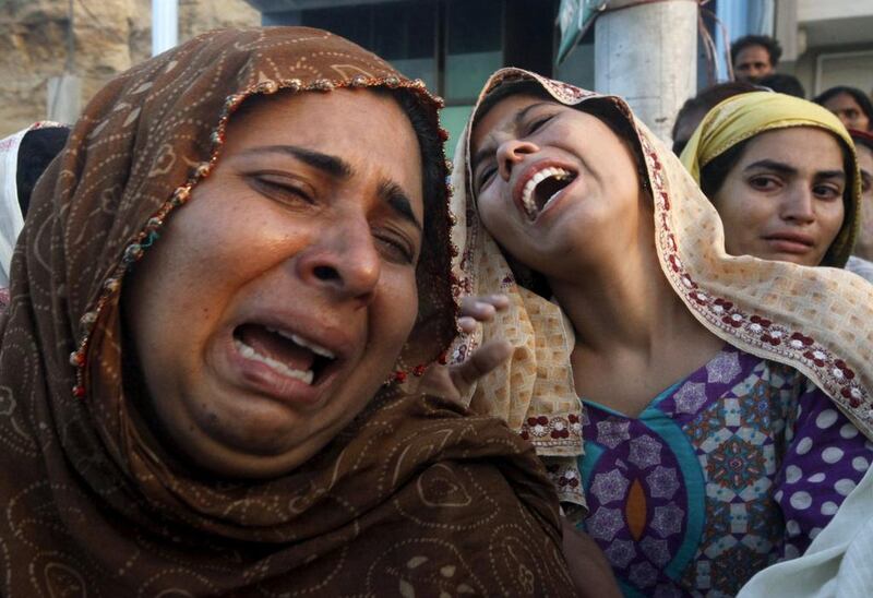 Relatives grieve upon seeing a body of a victim, that was pulled from the rubble of a landslide in the Gulistan-i-Jauhar area, in an ambulance in Karachi. Athar Hussain / Reuters