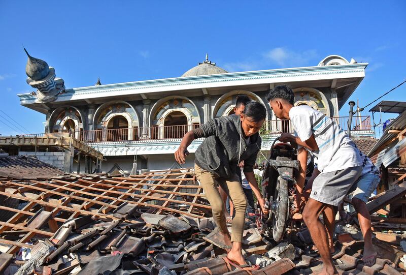 People recover a motorcycle from a damaged home near a mosque after a strong earthquake in Gunungsari, West Lombok. Reuters