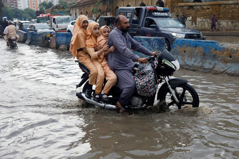 A family ride their motorcycle on a flooded road during the monsoon season in Karachi, Pakistan. Reuters