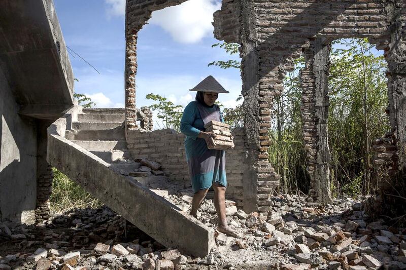 A woman works on the demolition site of a house in Sidoarjo. Ulet Ifansasti / Getty Images
