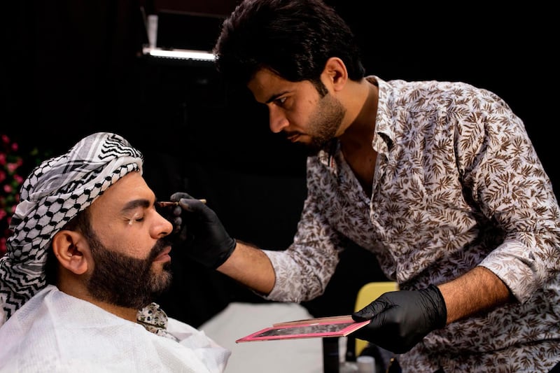 Iraqi actor Ayad al-Atabi, (L), gets his makeup done on the set of a parody sketch video of Bab al-Hara, an adaptation of an iconic long-running Syrian television drama, in Iraq's southern port city of Basra on April 22, 2020. AFP / Hussein Faleh