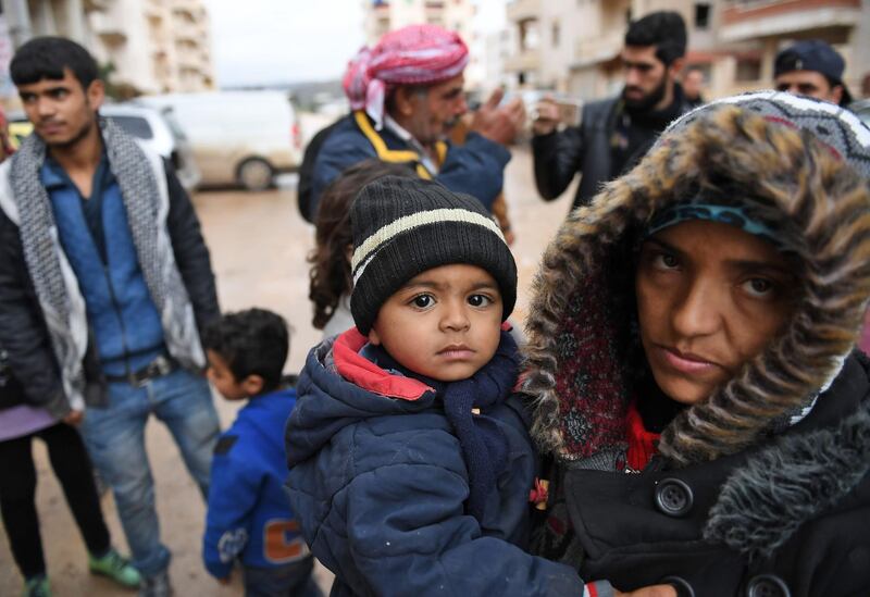 A Syrian woman carries a child as she arrives with others who fled from the town of Jandairis in the southwestern corner of the Afrin enclave, where Turkey and allied rebels have been conducting an offensive to oust Kurdish militias, in the city of Afrin on January 25, 2018.
Jandairis has been heavily targeted by Turkish air strikes and rockets as it sits close to the border and near a front line with pro-Ankara rebels. / AFP PHOTO / George OURFALIAN