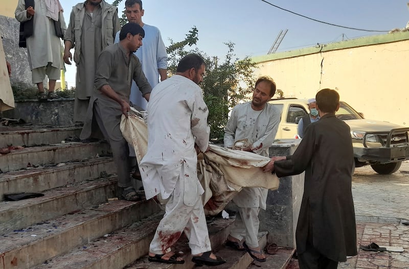People carry a body from inside the mosque.
