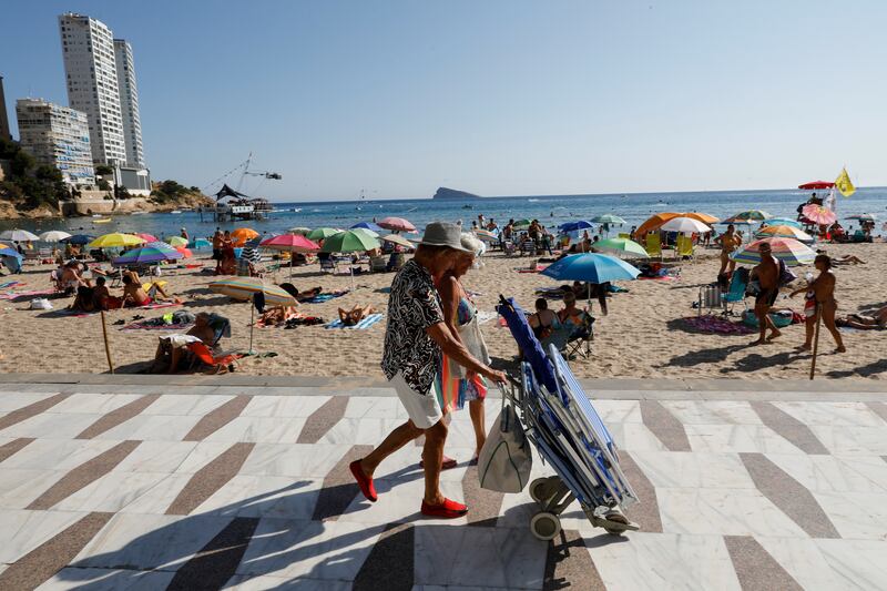 Holidaymakers walk along the Levante beach in Benidorm, Spain, where British tourists could face tougher restrictions. Reuters