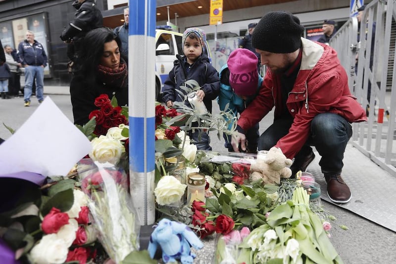 A family lays down flowers near the department store Ahlens following a suspected terror attack in central Stockholm. Markus Schreiber / AP Photo