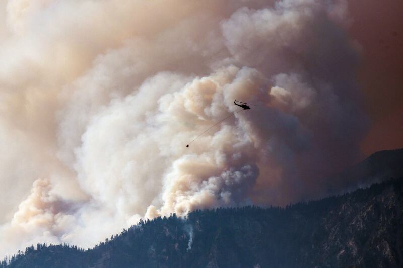 A helicopter prepares to make a water drop as smoke billows along the Fraser River Valley near Lytton, British Columbia, Canada, on Friday, July 2, 2021. Bloomberg