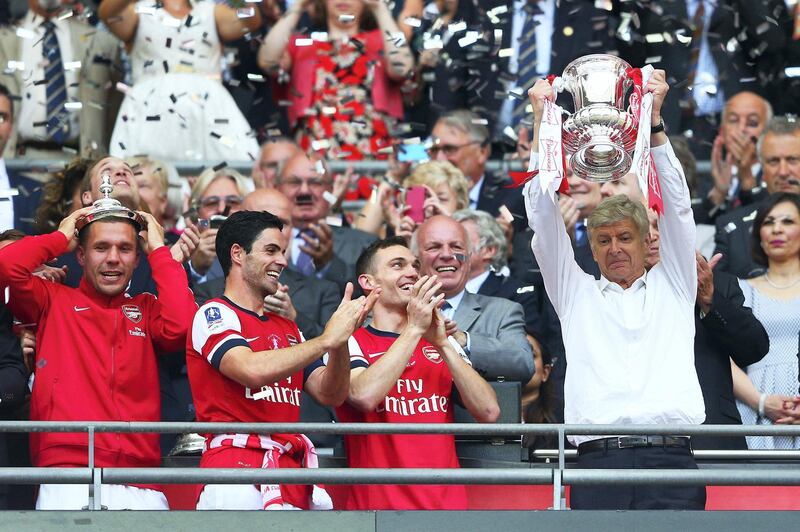 LONDON, ENGLAND - MAY 17:  Arsene Wenger manager of Arsenal (R) lifts the trophy in celebration alongside Lukas Podolski (L), Mikel Arteta (2L) and Thomas Vermaelen (2R) after the FA Cup with Budweiser Final match between Arsenal and Hull City at Wembley Stadium on May 17, 2014 in London, England.  (Photo by Clive Mason/Getty Images)