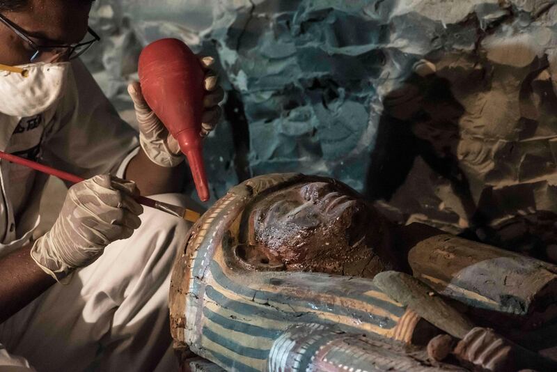 TOPSHOT - A picture taken on September 9, 2017 shows Egyptian archaeologist restoring a wooden sacrophagus at a newly-uncovered ancient tomb for a goldsmith dedicated to the ancient Egyptian god Amun, in the Draa Abul Naga necropolis on the west bank of the ancient city of Luxor, which boasts ancient Egyptian temples and burial grounds.
The finds at the tomb of "Amun's Goldsmith, Amenemhat", which dates back to the New Kingdom (16th to 11th centuries BC), also contained a sculpture carved into a recess of him seated beside his wife, with a portrait of their son painted between them, in addition to another 150 small funerary statues carved in wood, clay and limestone.
A burial shaft in the tomb led to a chamber where the archaeologists discovered mummies, funerary statues and masks, the antiquities ministry said. / AFP PHOTO / KHALED DESOUKI