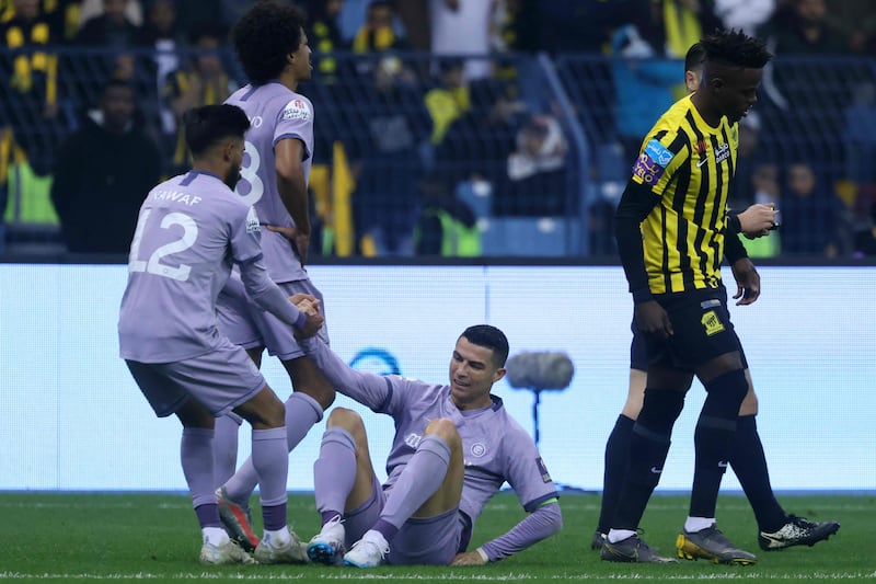 Al Nassr's Saudi defender Nawaf Boushal helps Cristiano Ronaldo back onto his feet. AFP